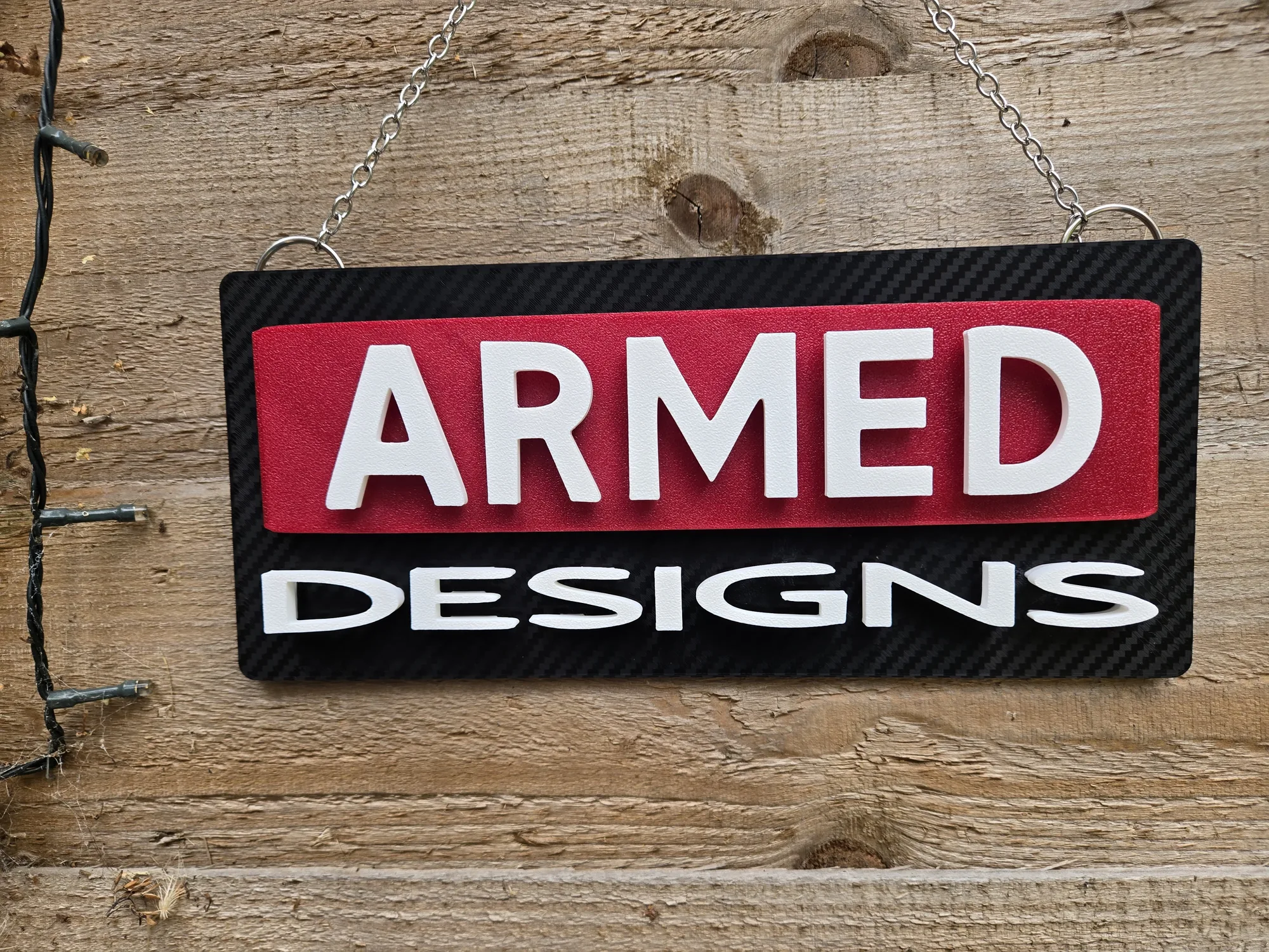 Front view of the ArmMed Designs hanging sign on a light wooden background.