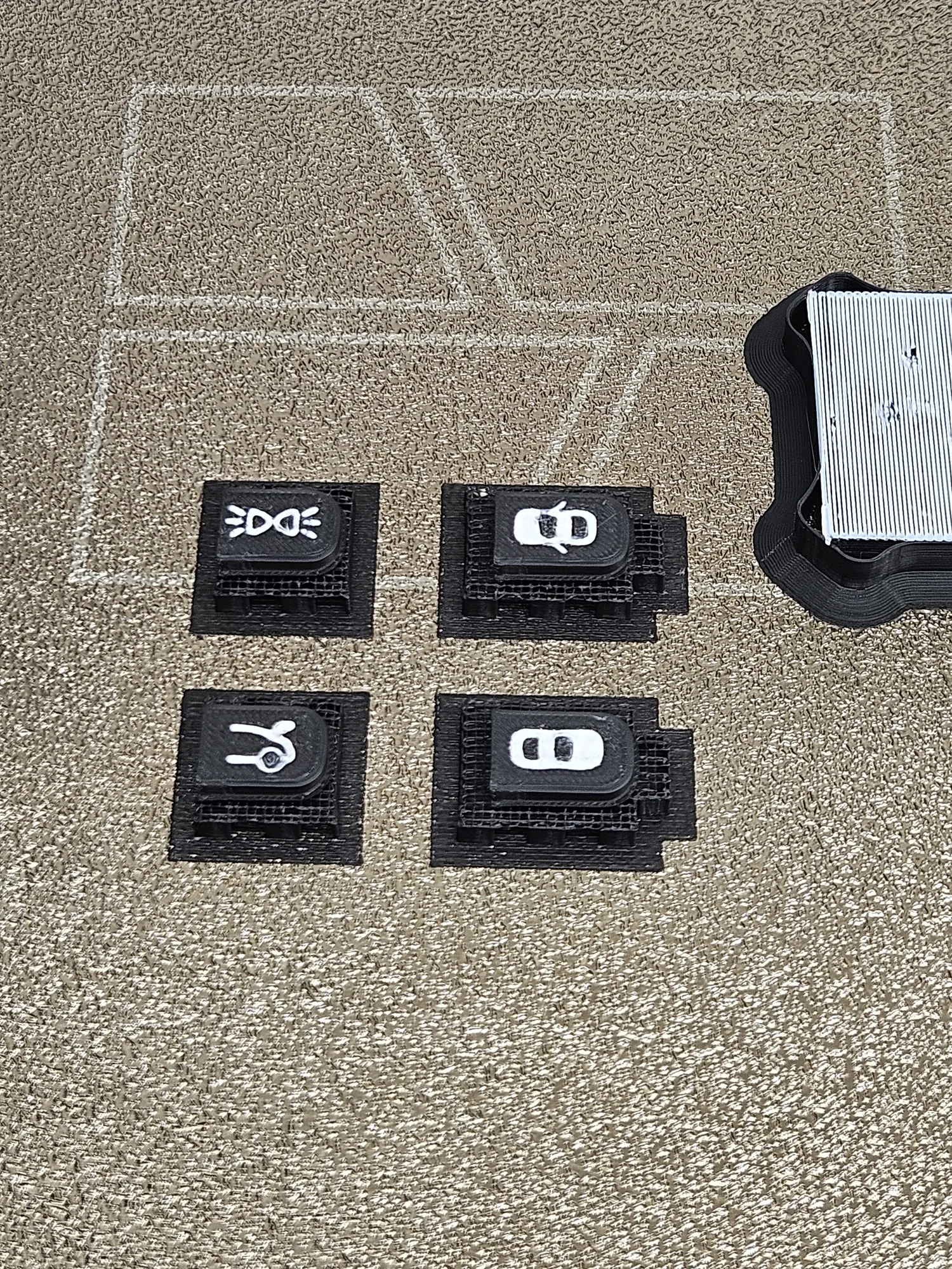 Four small replacement buttons on the printer bed during production.