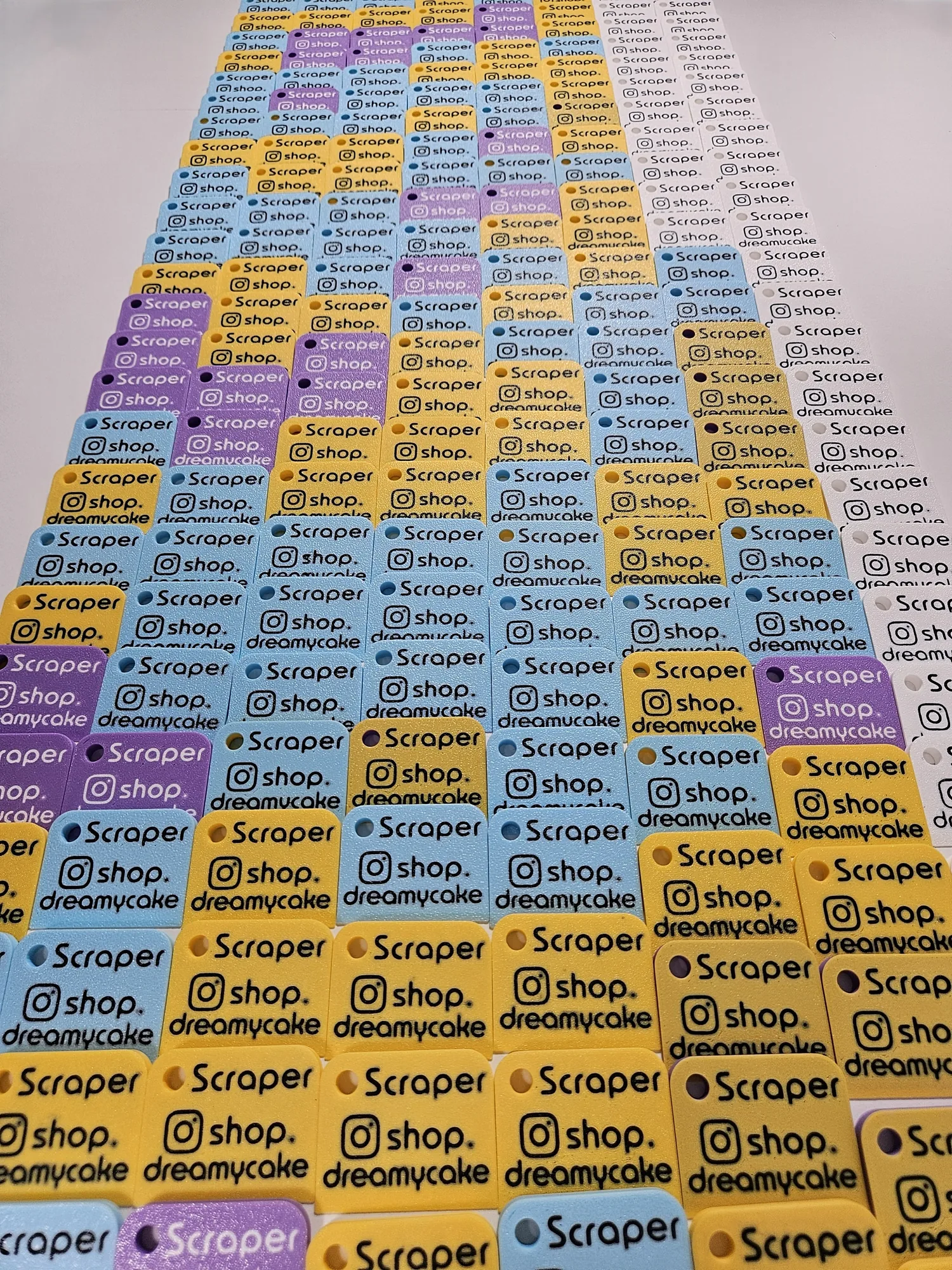 Large batch of 220 branded mini scrapers arranged with the text side visible.