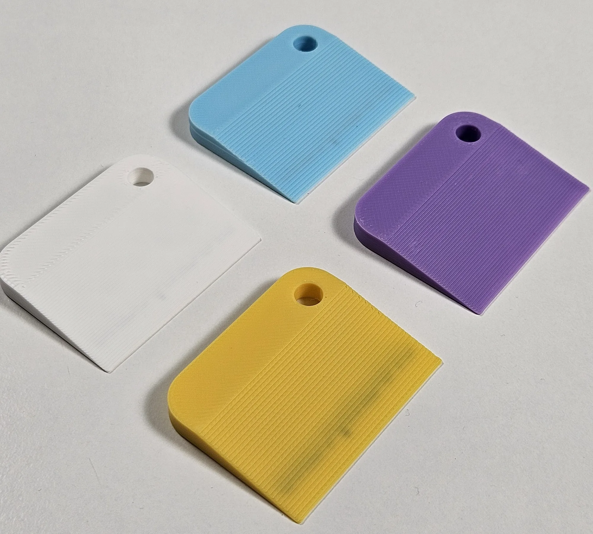 Four pastel-coloured branded mini scrapers shown at an angle.