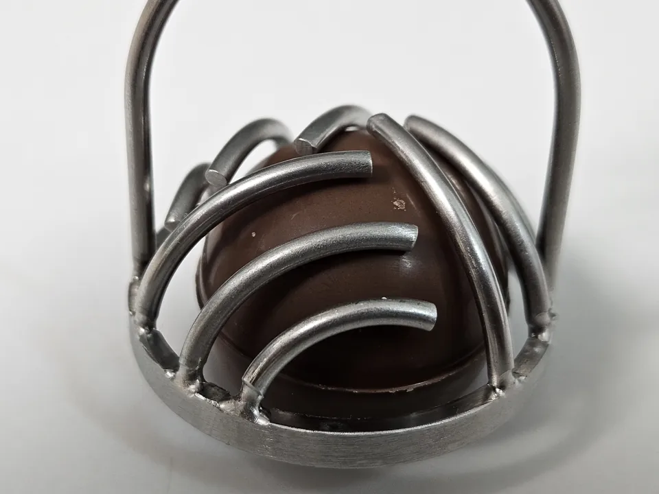 Close view of the original steel tool positioned over a chocolate sample.