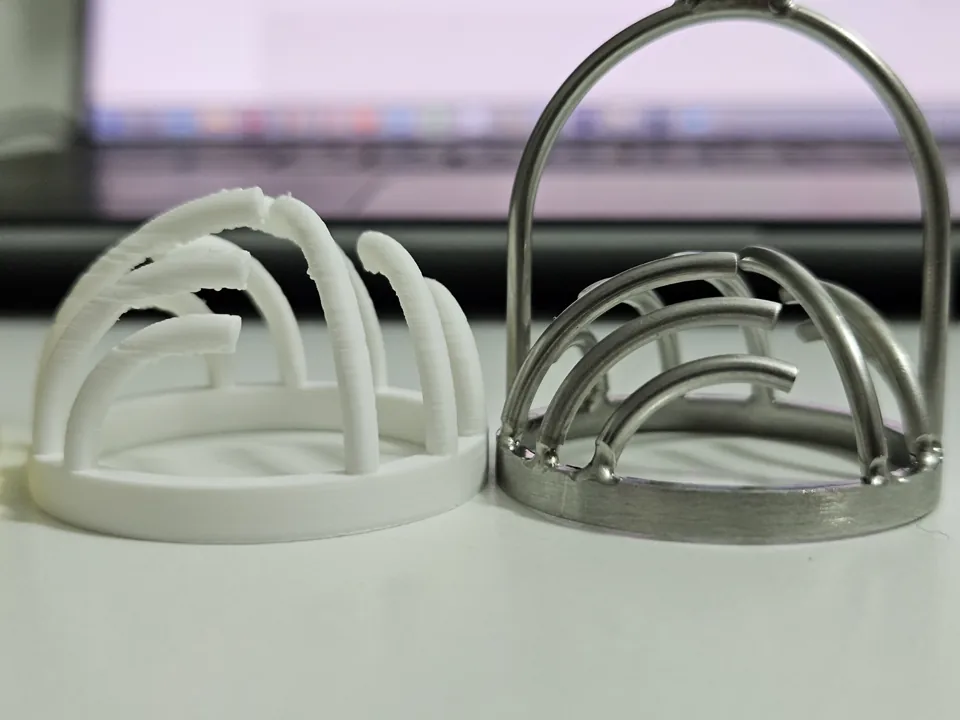 Side view of a white printed head beside the curved ribs of the metal original.