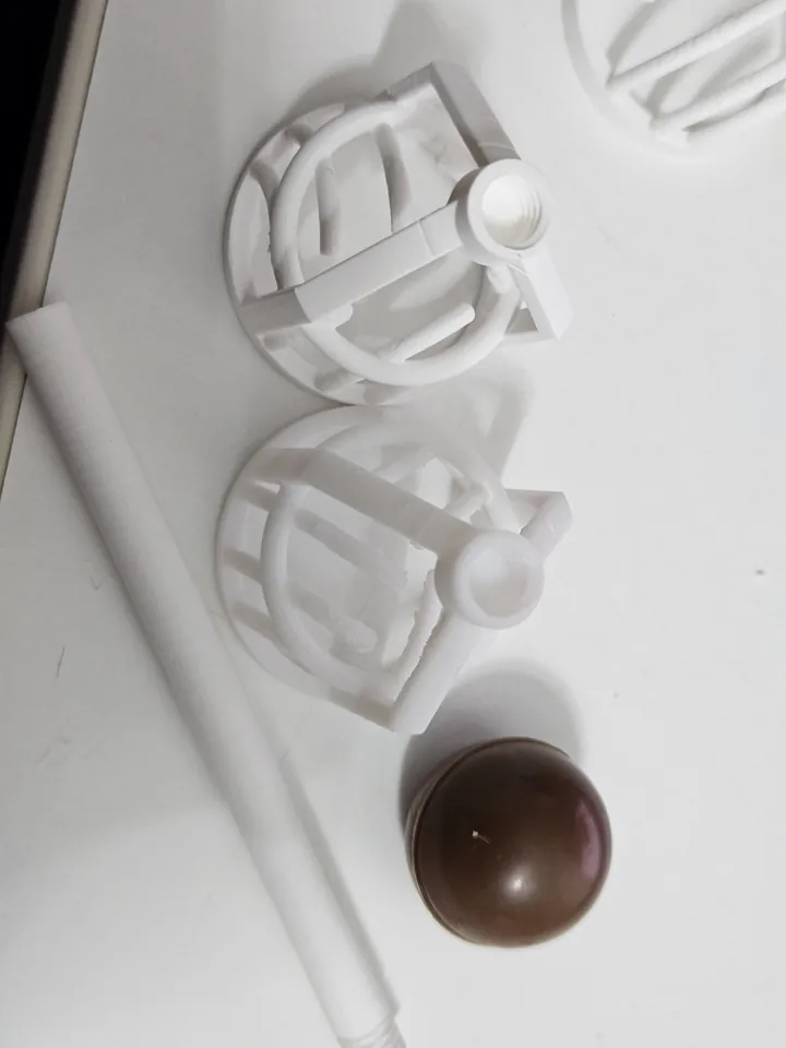 Two white prototype heads, a separate white handle and a chocolate sample on the work surface.