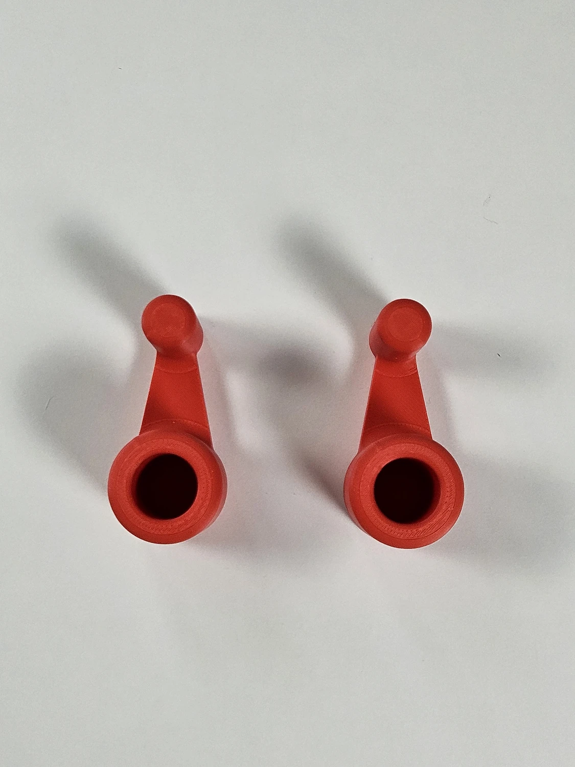 Small red laptop riser feet shown from above as a matched pair.