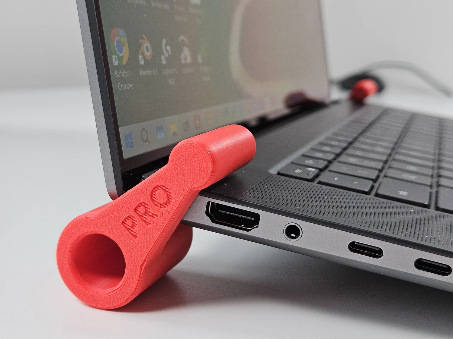 Red laptop riser foot fitted at the rear corner of a laptop.