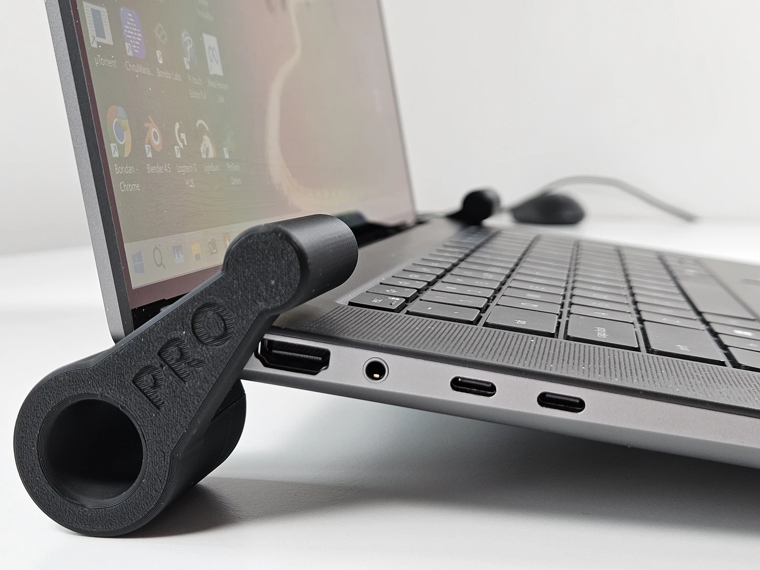 Laptop fitted with black clip-on riser feet at the rear.