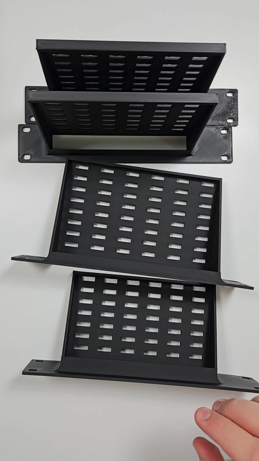 Four black custom rack-mount adapters laid out together on a table.