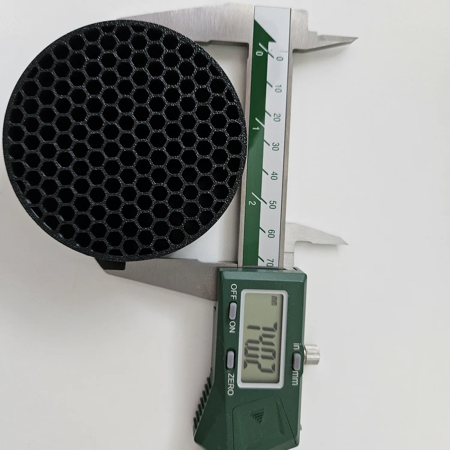 Measuring the diameter of a custom intake flow straightener with a digital caliper.