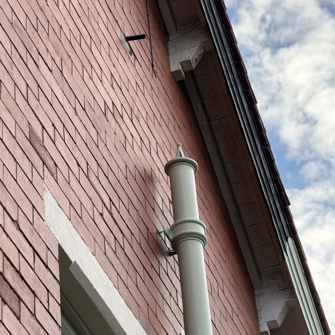 Painted custom roof vent cowl installed on the outside of a brick building.