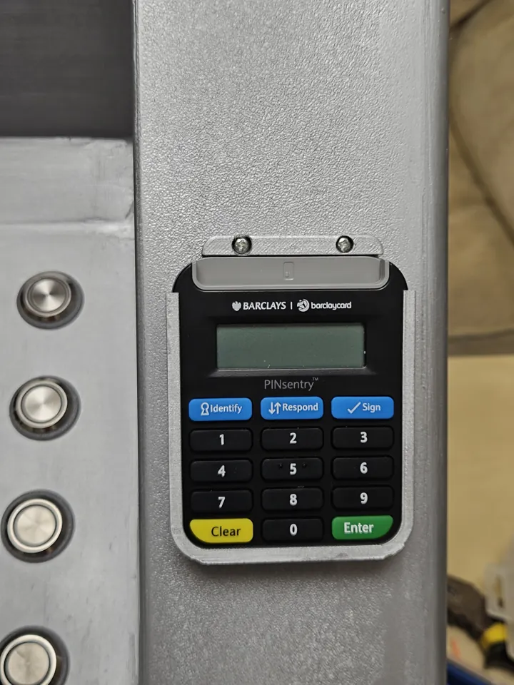 Authentication device held in a printed pocket with a bolted retaining strip above it; its display is blank.