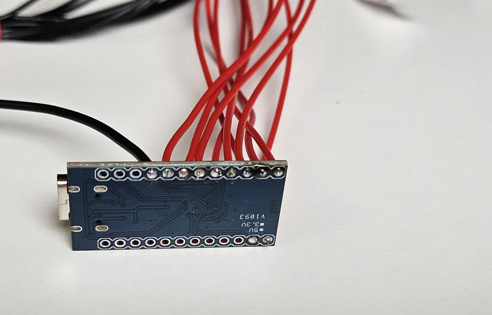 Arduino Pro Micro board with wires soldered along one side.
