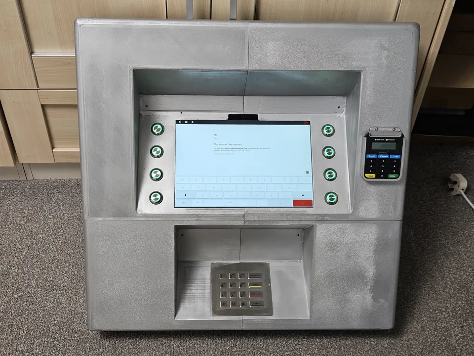 Front of the assembled kiosk with a fitted tablet, eight green illuminated buttons and metal keypad.
