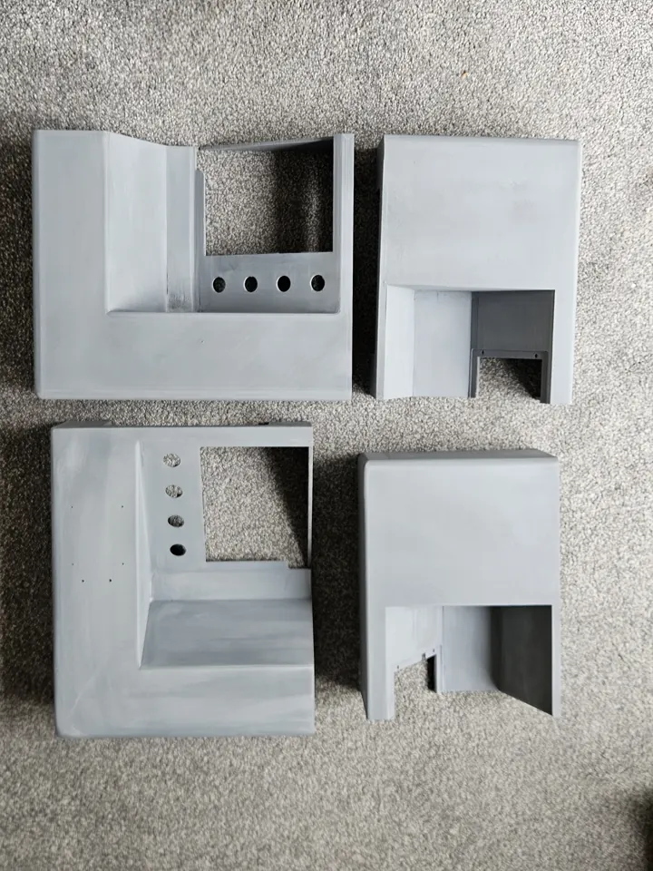 Four grey enclosure sections laid out before final assembly.