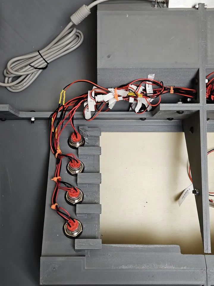 Rear of several mounted buttons with labelled wires routed around the screen opening.