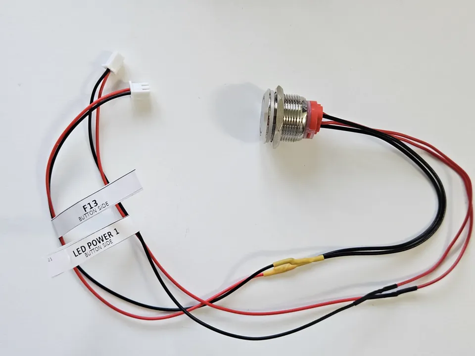 Illuminated metal button with two labelled wire connections.