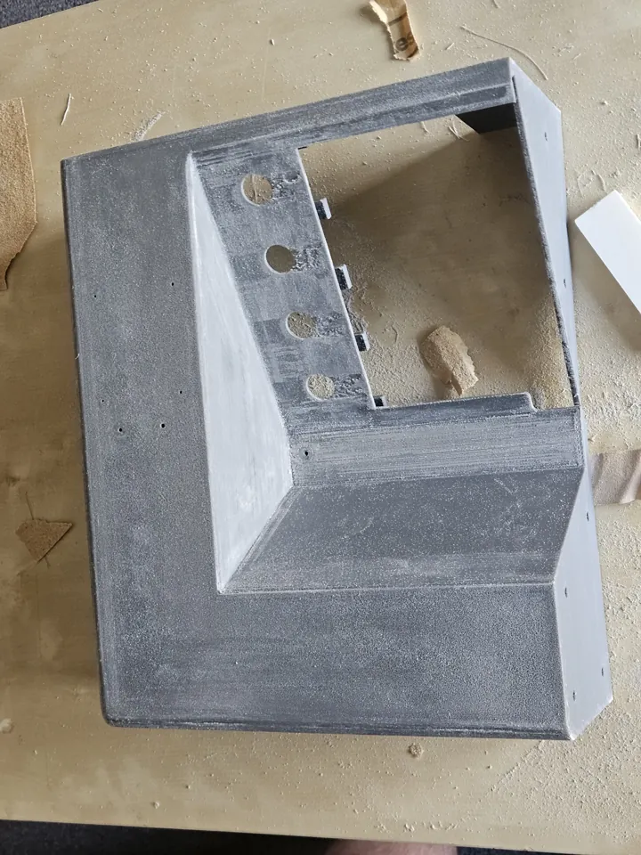 Partly finished grey enclosure section on a work surface with filled and sanded areas.