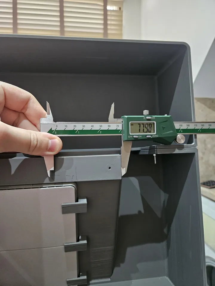 Calipers measuring clearance beside the tablet at the rear of the enclosure.