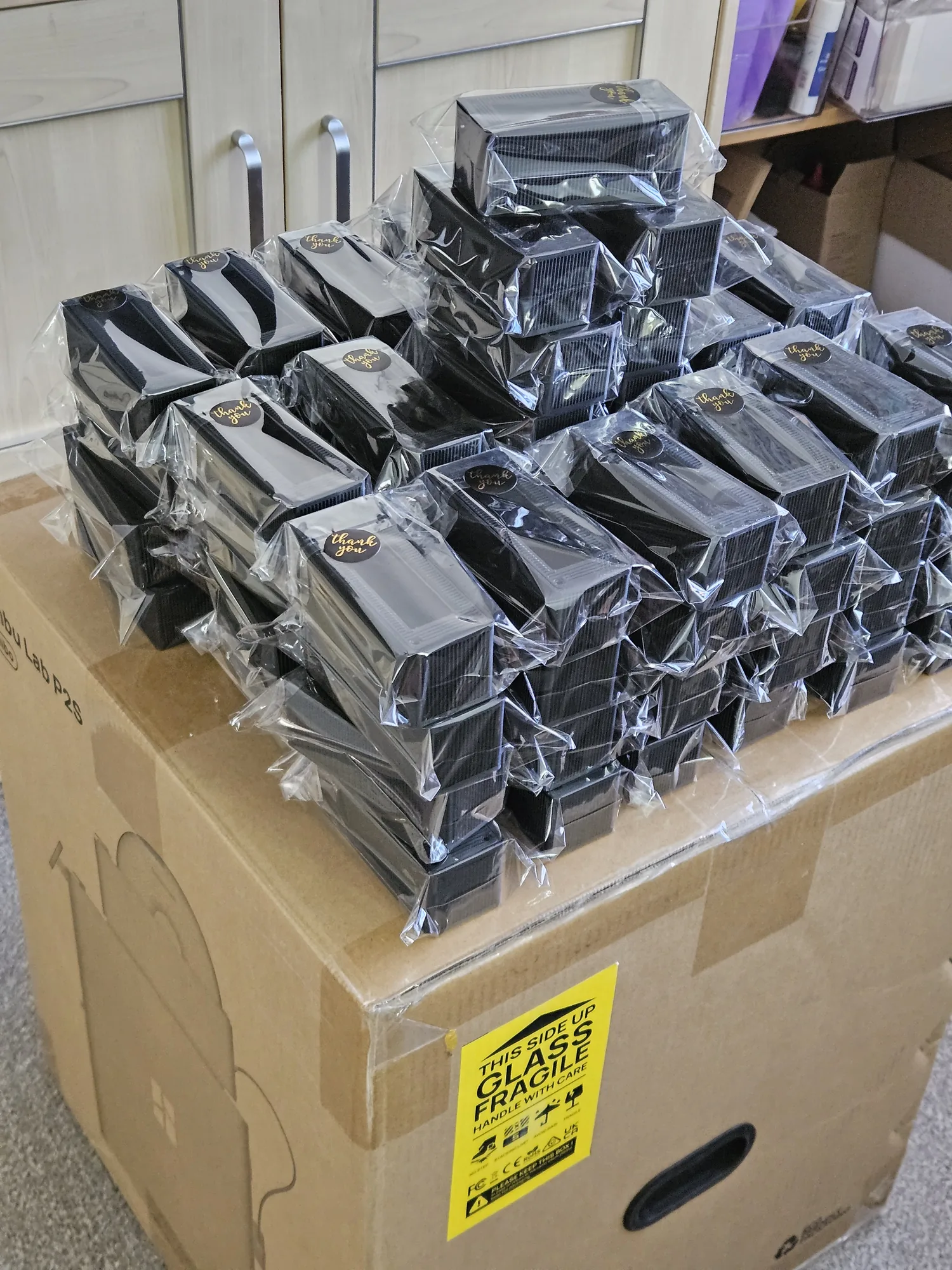 A large batch of black enclosures individually bagged and ready for final packaging.