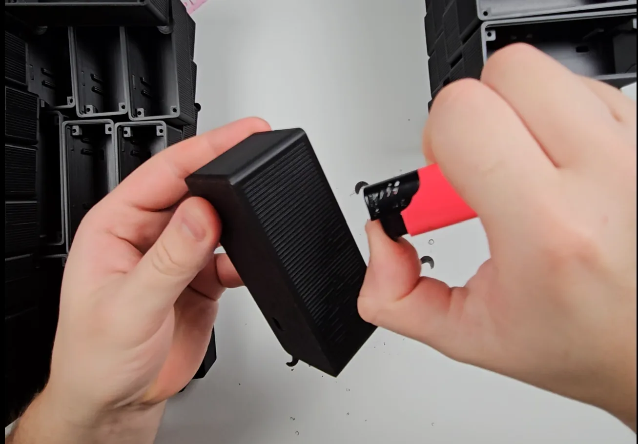 Flame finishing a black PLA enclosure to remove fine stringing.