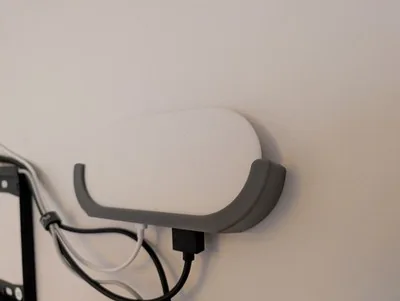 White Google TV Streamer installed in a grey wall holder with cables connected.