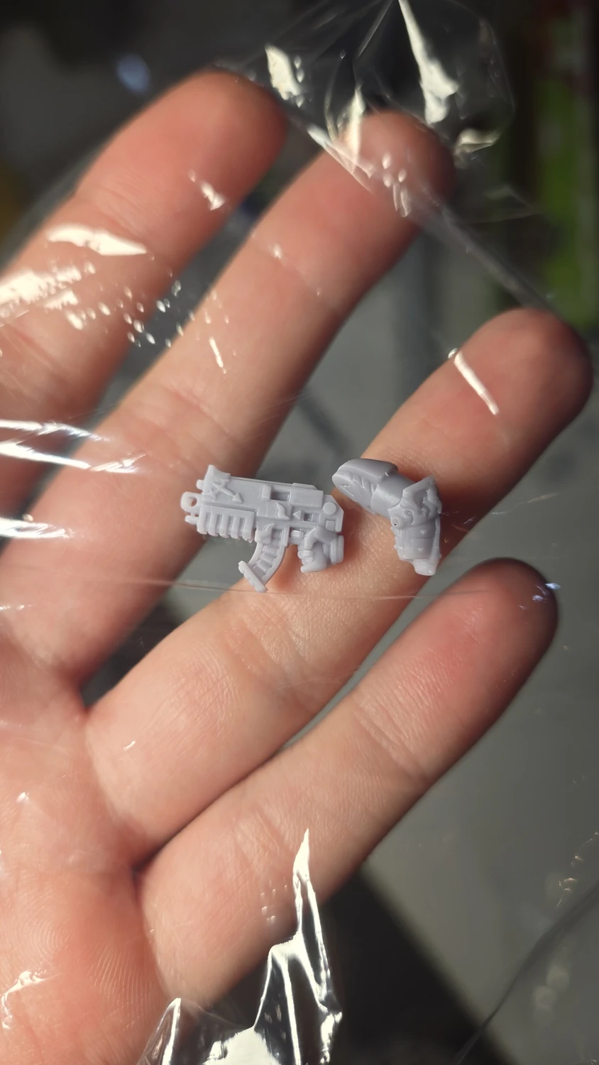 Tiny resin weapon parts resting in a hand for scale.