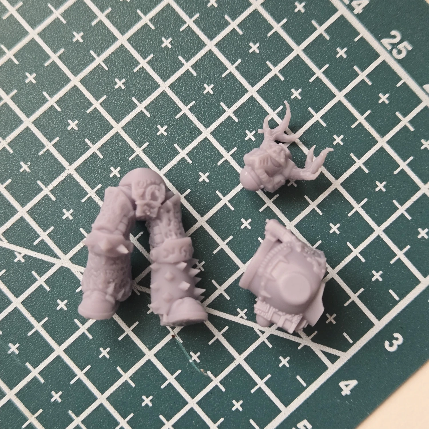 Small resin orc body parts laid out on a cutting mat.