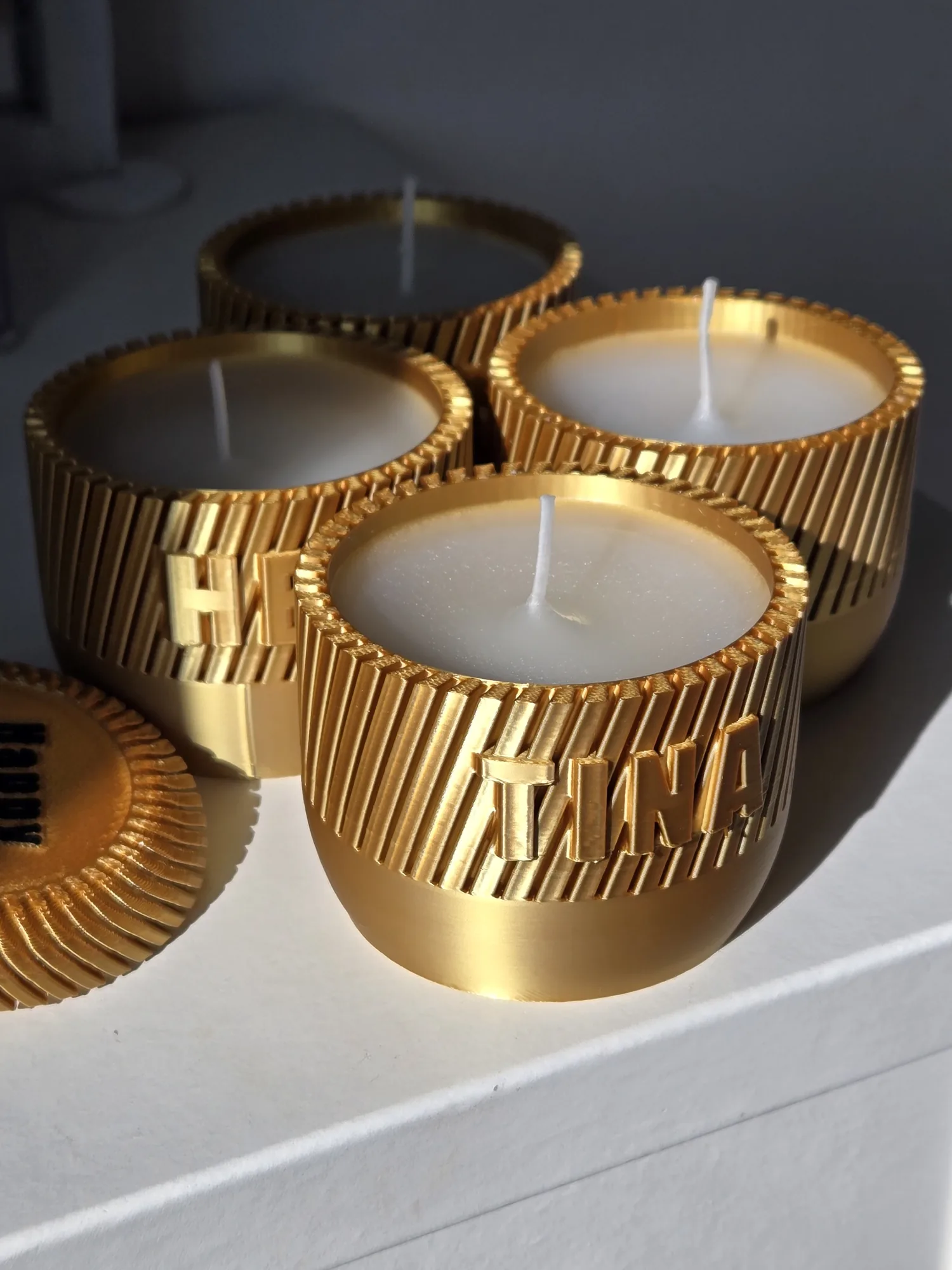 A small batch of personalised candle jars printed in a metallic gold colour.