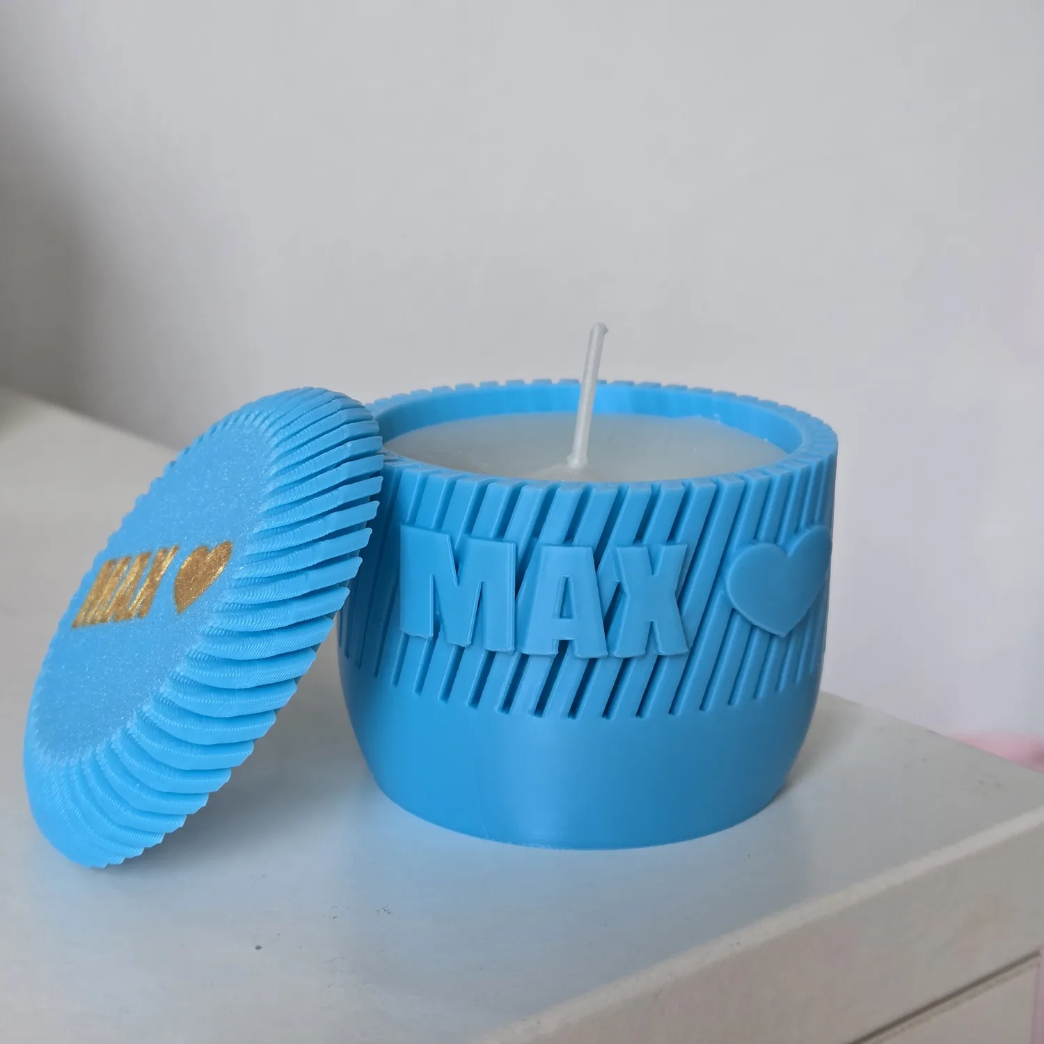 A personalised candle jar with a matching lid, showing the ribbed texture and raised lettering.