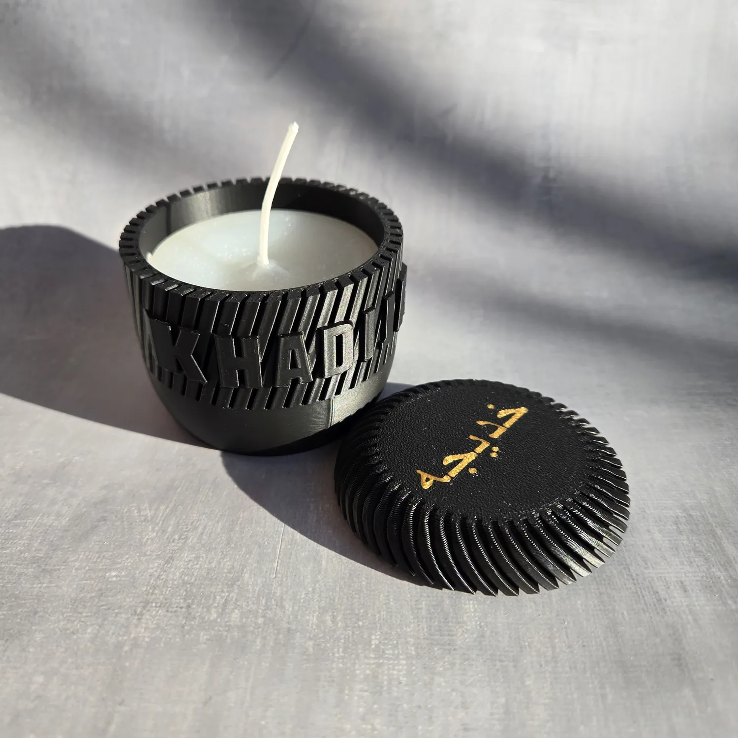 A personalised candle jar showing custom text in a non-English language.