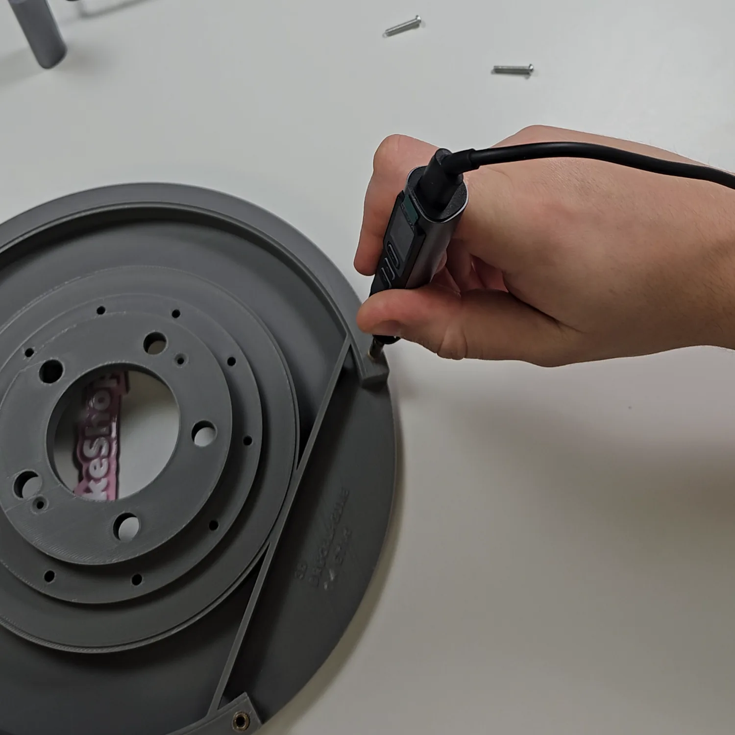 Installing brass heat-set inserts into a 3D printed brake disc lamp component.