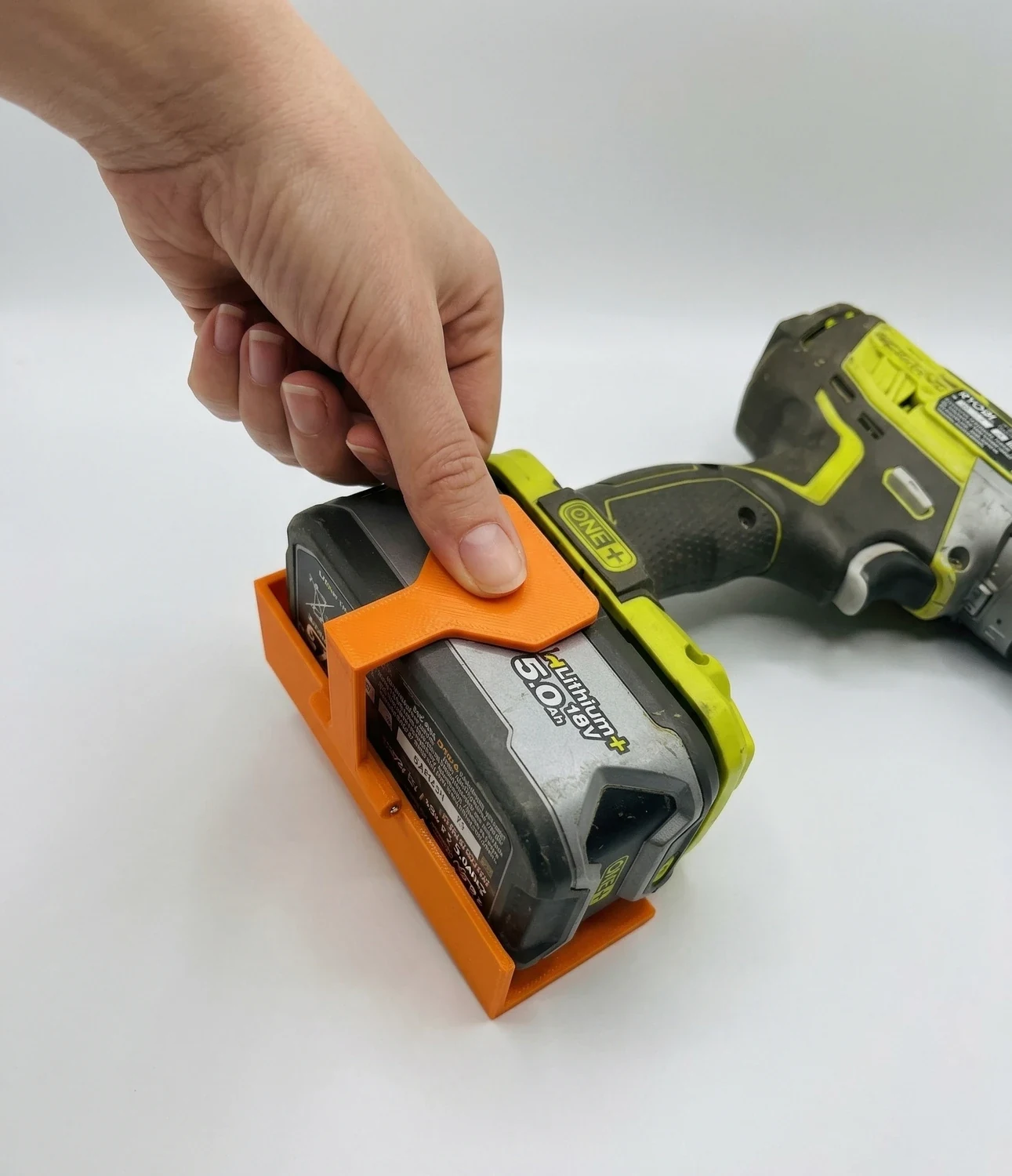 Orange Ryobi ONE+ battery removal tool being used to pull a battery from a tool.