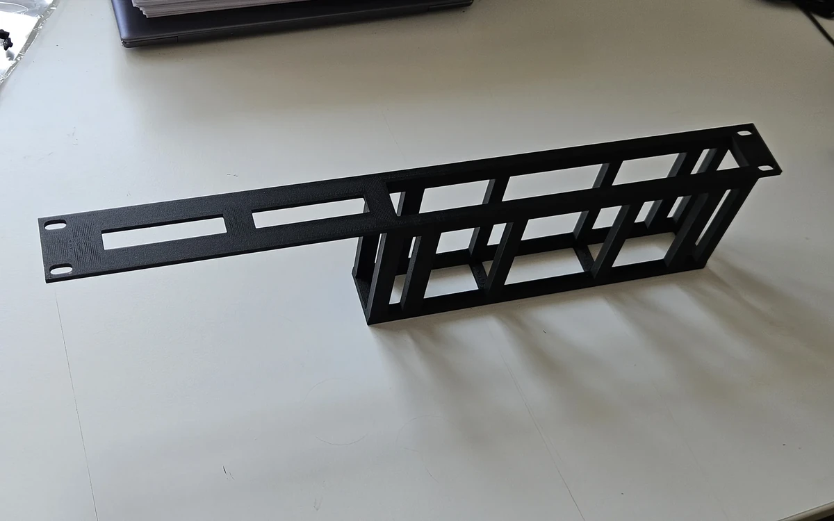 One-piece black rack adapter for a Zyxel XMG1915-10E switch.