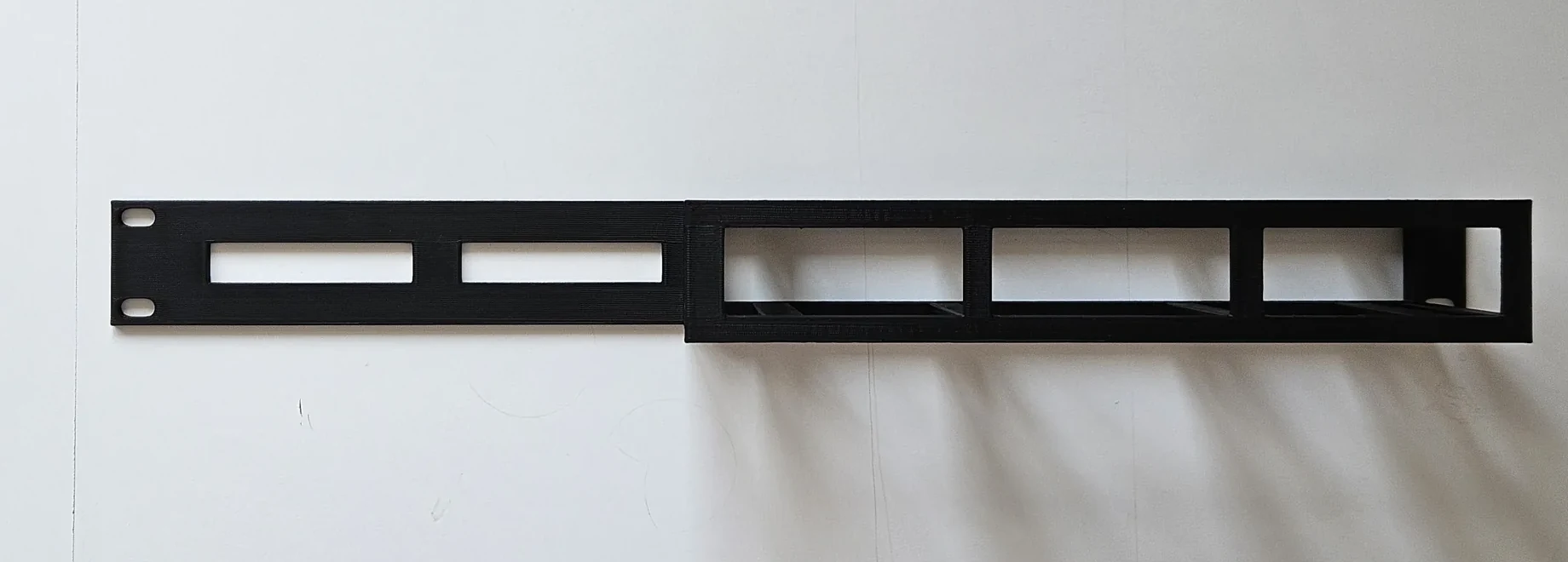 Front view of the finished black adapter showing the switch opening and long cable-routing slots.