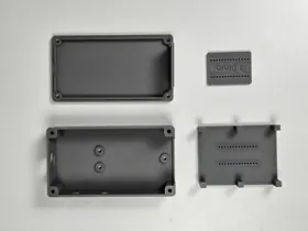Printed enclosure parts and small-hole test pieces.