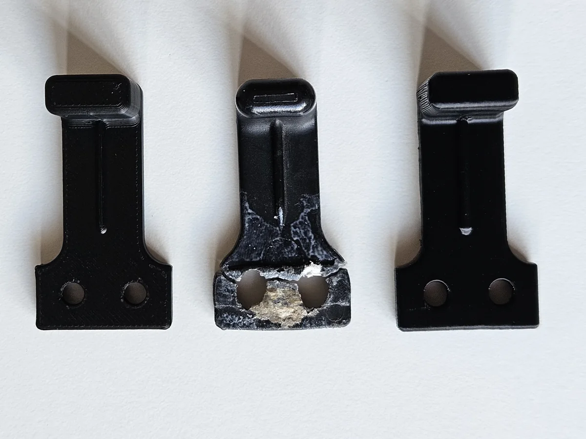 Broken campervan insect-screen handle between two newly printed replacement handles.