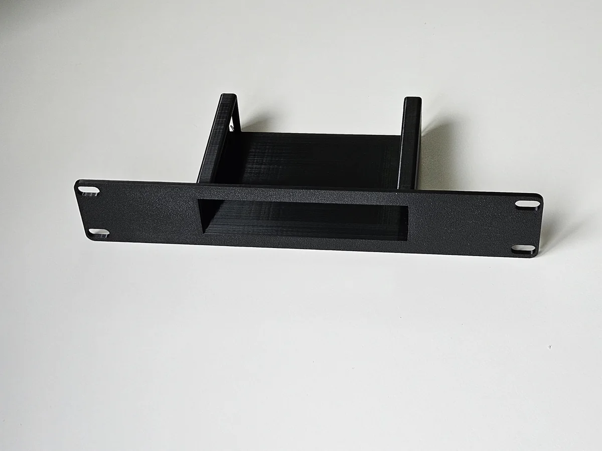 Black custom rack-mount adapter with a fitted device opening and ventilated support basket.
