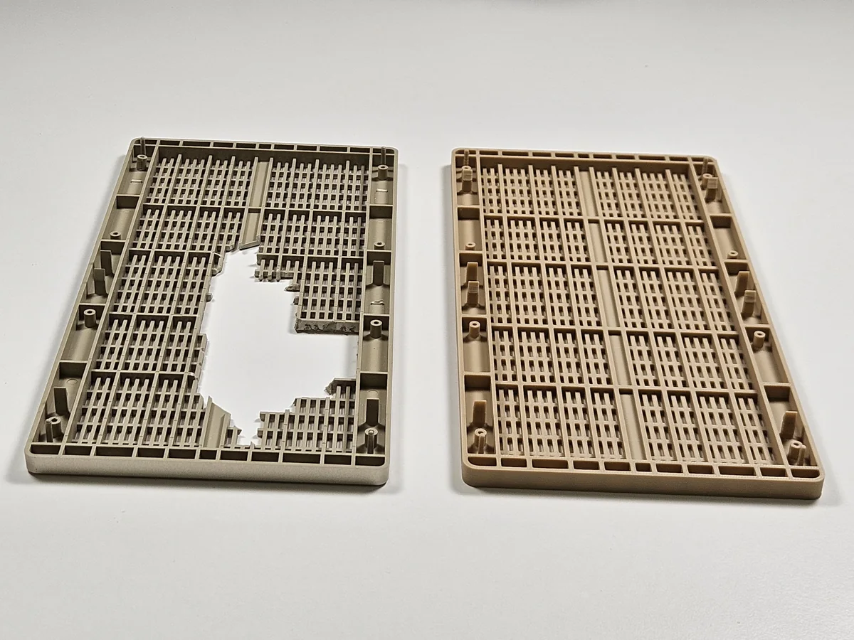 Rear views of the broken original radio grille and printed replacement side by side, showing ribs, screw posts and mounting features.